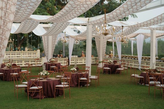 Espace de réception de mariage en extérieur sous voilages avec tables dressées